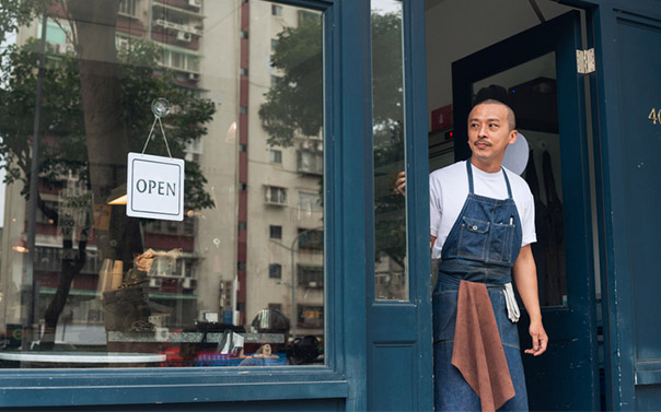 Business owner standing in their store front with open sign